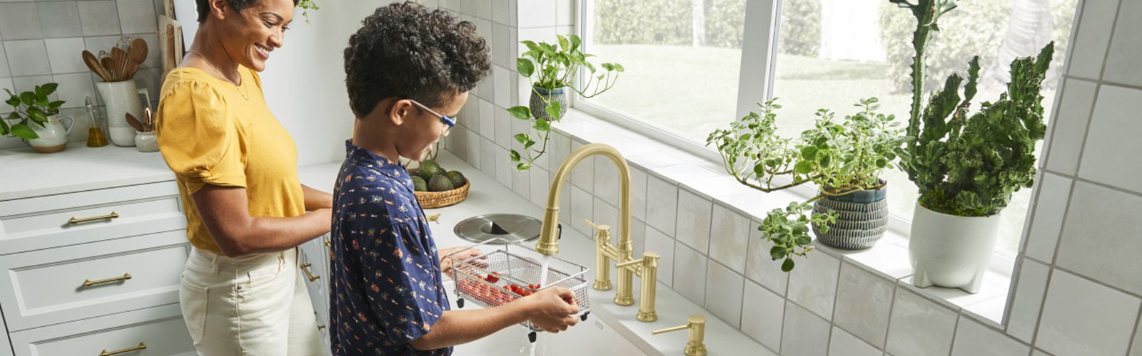 Son and mom in kitchen washing tomatoes